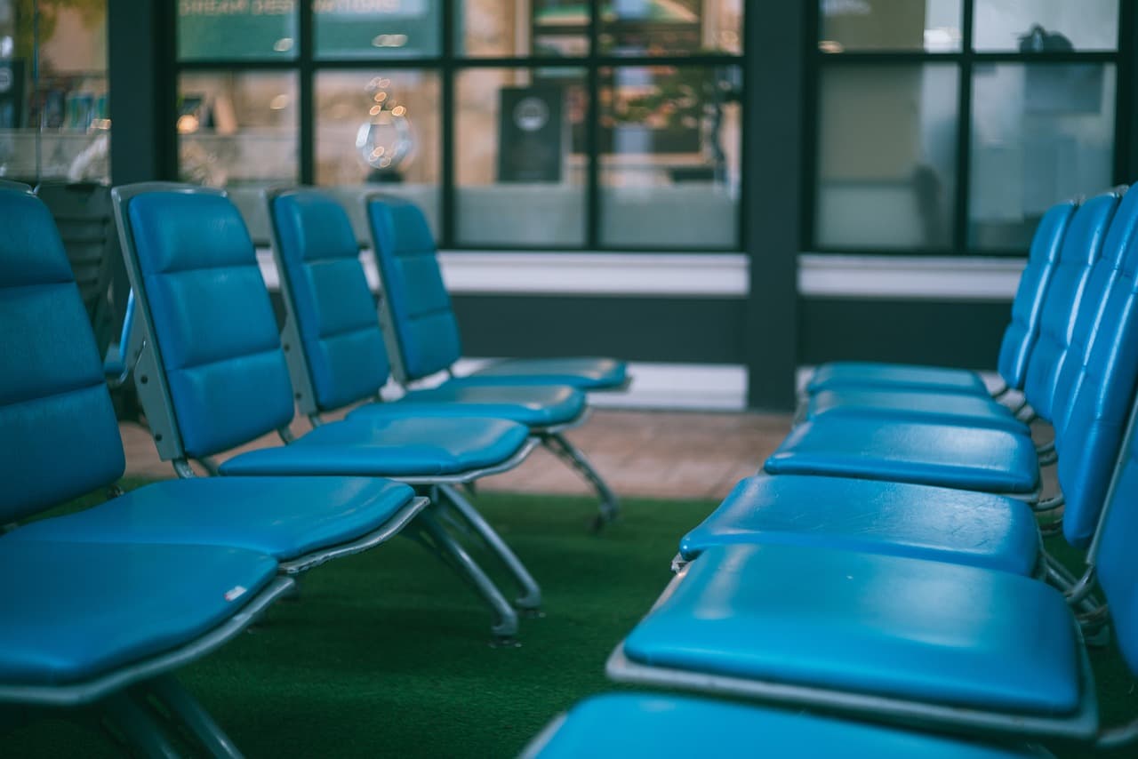 A row of padded waiting-room chairs by a window